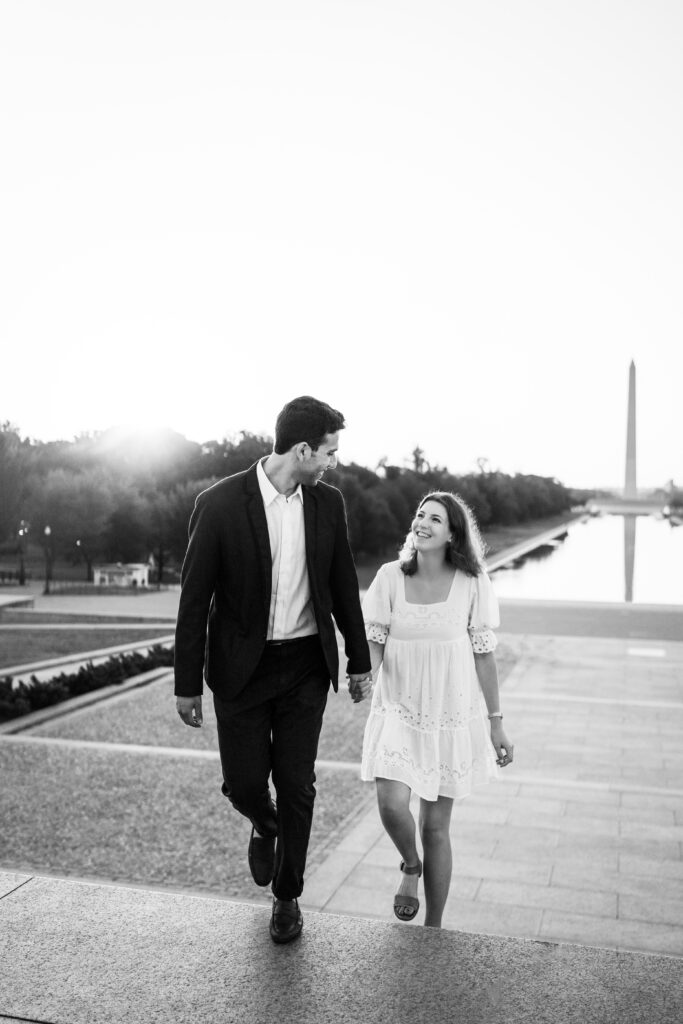 Emma and Fady standing hand in hand with the Washington Monument in the background during a sunrise in Washington DC.