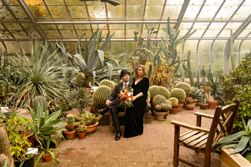 A bride and groom in their wedding attire pose for portraits inside the lush cactus room of the Lamberton Conservatory in Highland Park.