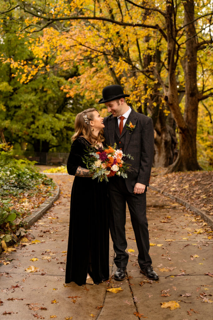 Bridal portraits from a Halloween Wedding in Highland Park. The bride is wearing a flowing black dress, and the groom is wearing a dapper suit with a top hat. The bride's wedding bouquet is a beautiful fall palette of white, rust, and dark purples. 