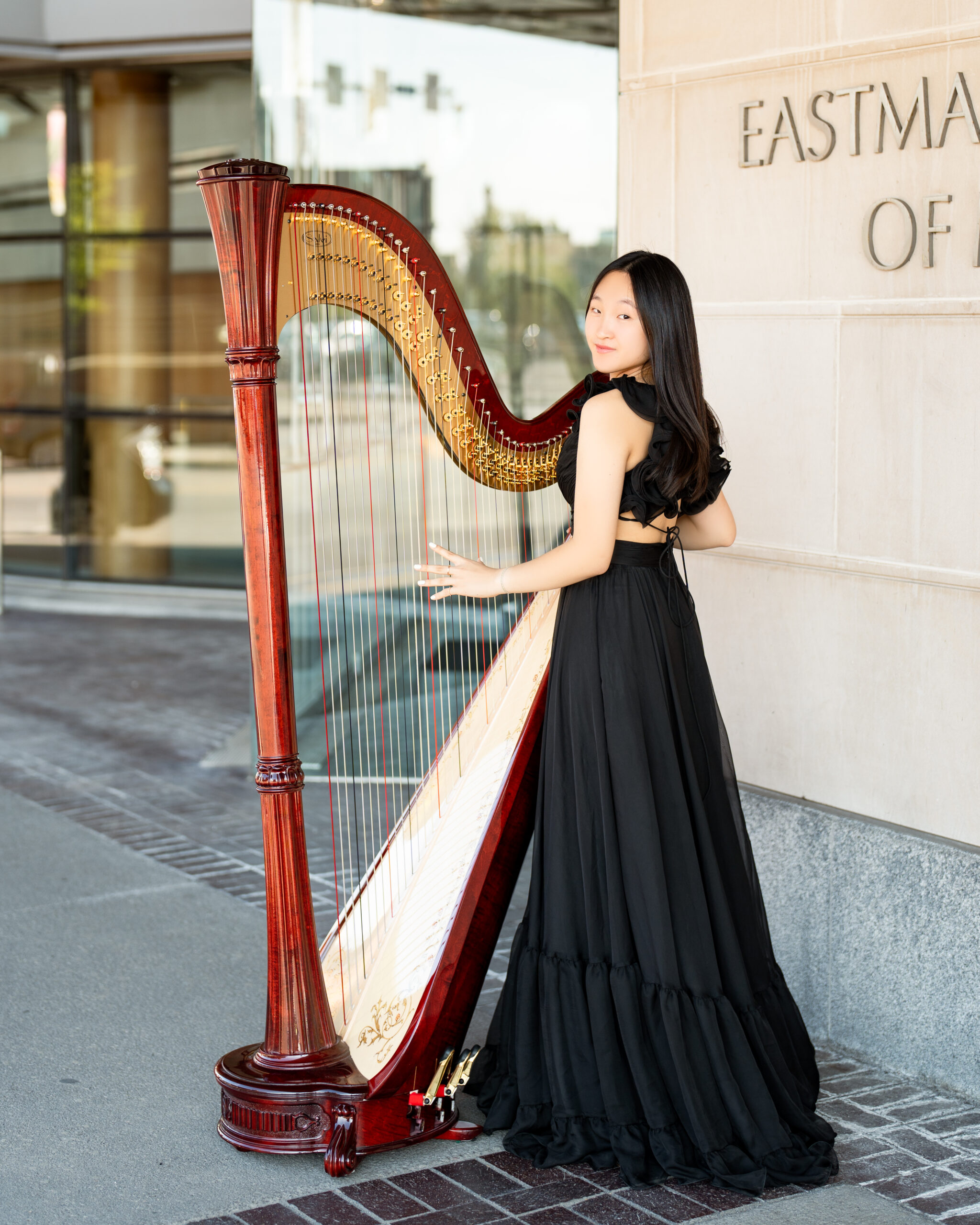These Rochester senior pictures feature a high school senior and her harp. She is wearing a long, black dress with a large harp.
