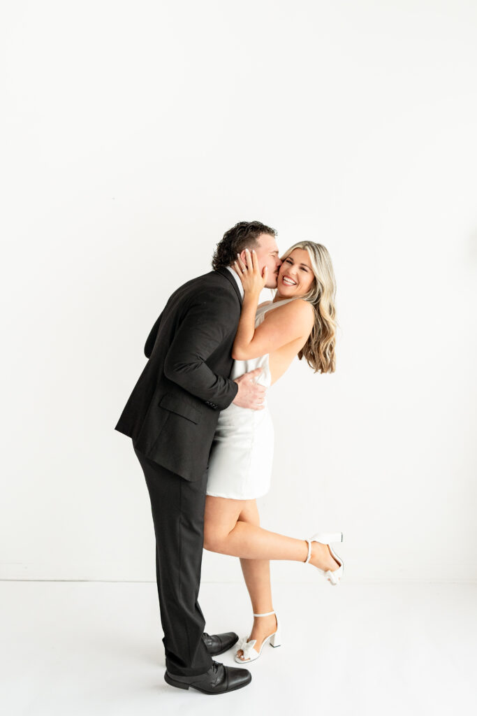 This photo depicts a modern, yet timeless engagement session at Gallery 48. This session features a couple named Jill and Ray, and they wore a formal outfit. They are pictured in an all white studio.